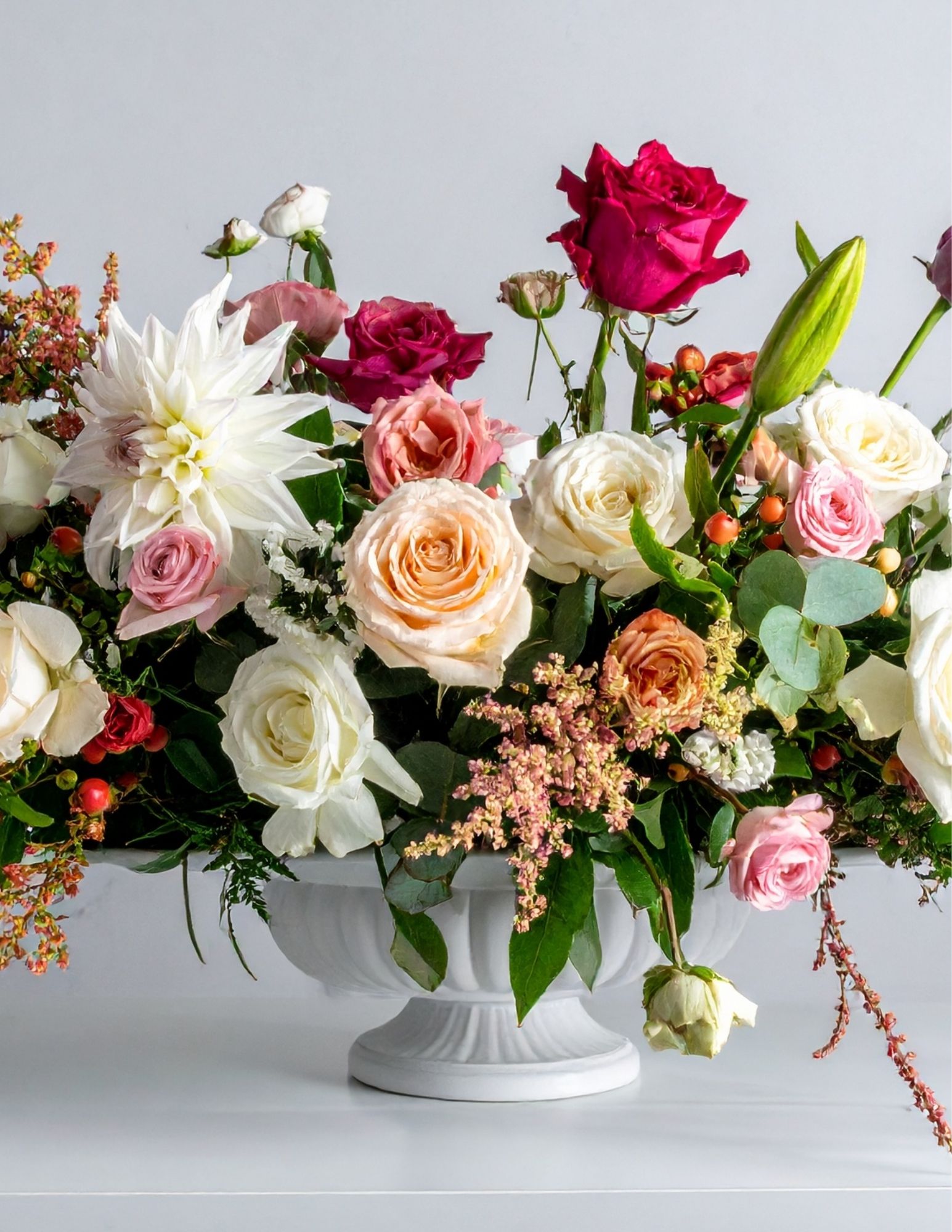A white compote vase with pastel color flowers